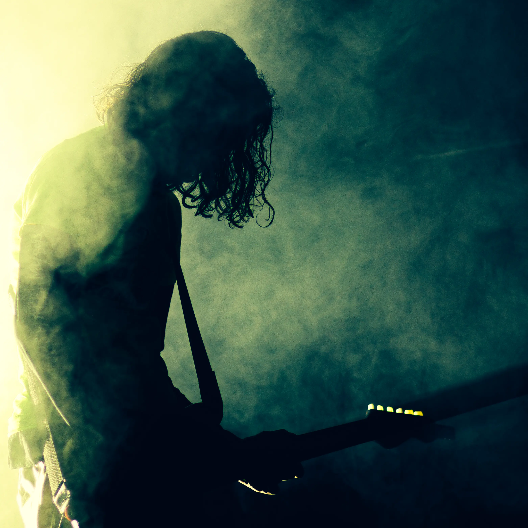 Le musicien faisant de la guitare, à contre jour dans de la fumée verte
