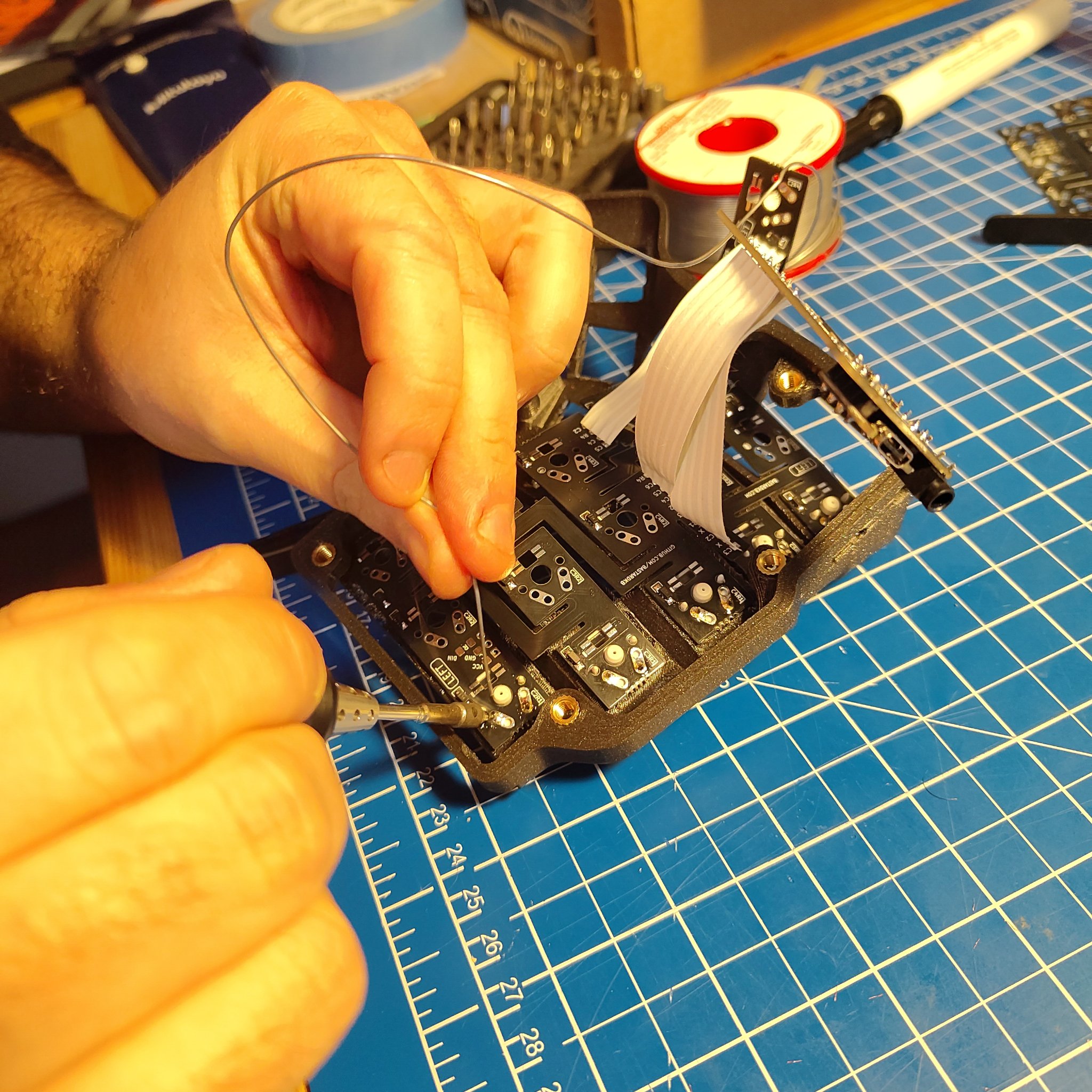 Deux mains qui soudent un switch sur un PCB flexible, mit en place dans une case imprimée en 3D