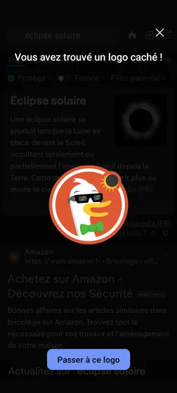 Le logo du moteur de recherche Duck Duck Go, c'est-à-dire une tête de canard blanc et souriant avec un petit nœud papillon vert dans un cercle orange. Exceptionnellement, il est représenté en train de regarder une éclipse solaire, à l'aide de lunettes de protection spéciales.