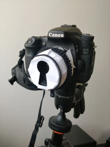 Un APN Canon 70D avec un cache en papier sur l’objectif don une forme de serrure a été découpée.