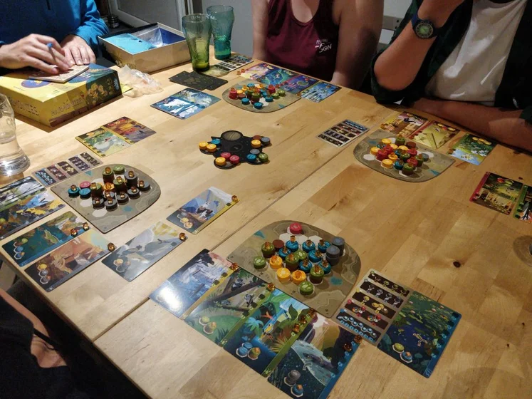 Photo d’une taable avec les plateaux de jeux entouré des personnes