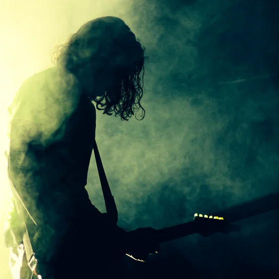 Le musicien faisant de la guitare, à contre jour dans de la fumée verte