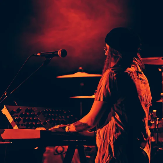 La claviériste du groupe sur son synthétiseur, lumière rouge